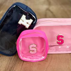 three bags sitting on top of a wooden floor next to each other, one pink and one blue