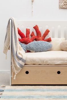 a bed with pillows and blankets on top of it next to a rug in front of a wall