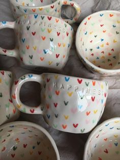 a group of ceramic bowls and cups with hearts painted on them