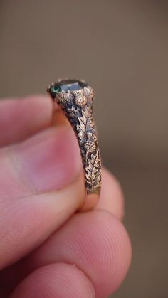 a close up of a person's hand holding a ring with an ornate design on it