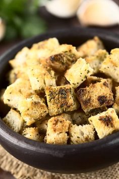 a bowl filled with tofu sitting on top of a table next to garlic and parsley