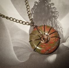 A vibrant green and pink unakite stone "donut" pendant is wrapped in copper tone wire forming a spiral in the center. It is fixed to a matching chain with a lobster clasp closure, measuring 9 inches, 18 in total. Unakite can provide you with healing, balance, patience, determination & resilience. Donut Bead Jewelry, Donut Pendant, Claw Necklace, Wrapped Necklace, Crystal Necklaces, Wire Wrapped Necklace, Bead Jewelry, Green And Pink, Vibrant Green