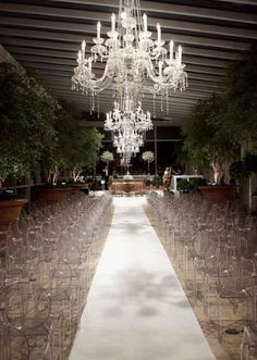 the aisle is lined with clear chairs and chandeliers