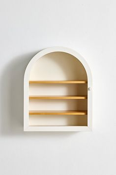 a white wall mounted shelf with three wooden shelves on one side and an arched opening to the other