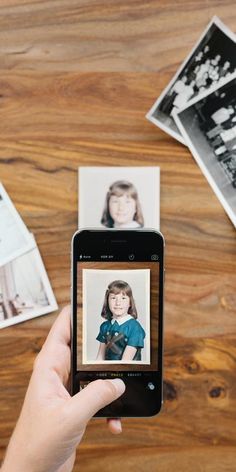 a person holding up a cell phone with an old photo on the screen next to them