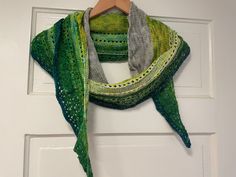 a green shawl hanging on a white door