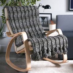 a chair with a blanket on it in front of a couch and potted plant