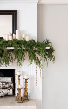 a mantel with candles and greenery on it