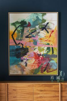 an abstract painting hangs on the wall above a dresser