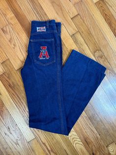 "1970s 80s University of Alabama Crimson Tide Blue Denim Jeans 26\" Waist TALL  University of Alabama patch on rear pocket Straight leg semi boot cut ish Front and back pockets  High waist Fits best on someone with slender hips, less curves  Waist: 26\" / 27\" - 28\" snug Upper hips: 30\" Hips: 34\" Length: 47\" Inseam: 36\" Rise: 10.5\"//11\" Great condition, there's a few light spots, not sure if they're bleach or chemical stains from older days, see photos" Retro Mid-rise Cotton Flare Jeans, Vintage Cotton Flare Jeans For Fall, Vintage Style Cotton Flare Jeans For Fall, Retro Denim Blue Cotton Flare Jeans, Vintage Denim Flare Jeans For Fall, Retro Blue Cotton Flare Jeans, Retro Flare Jeans For Fall, Retro Dark Wash Cotton Flare Jeans, Retro Denim Flare Jeans With Pockets