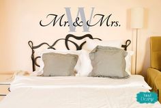 a bed with two pillows on top of it next to a wall that says mr and mrs