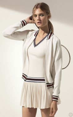 a woman is posing with a tennis racket in her hand and wearing a white outfit