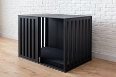 a black cabinet sitting on top of a hard wood floor next to a white brick wall