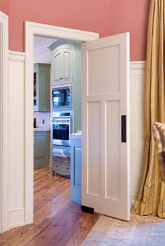 an open door leading to a kitchen with pink walls and wood floors in the background