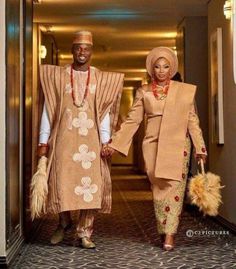 two people dressed in african attire walking down a hallway