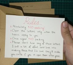 a hand holding a piece of paper that has been written on it and is in front of some envelopes