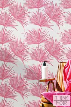 a pink wallpaper with palm leaves on it and a white bottle next to it