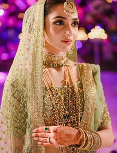 a woman in a bridal outfit with jewelry on her head and hands clasped together