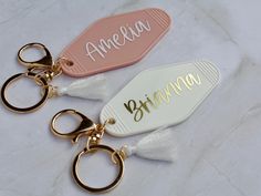 two personalized key chains with tassels on them