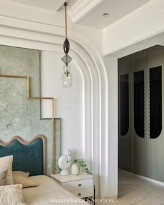 a bedroom with white walls and an arch in the ceiling, along with a blue headboard