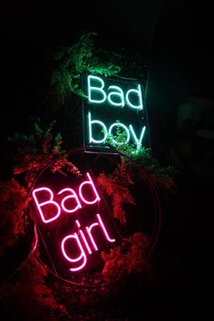 two neon signs that say bad girl and bad boy on them in front of some bushes