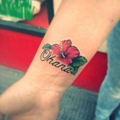 a person with a flower tattoo on their wrist and the word hawaii written in cursive writing