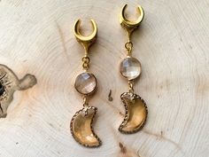 two pairs of earrings sitting on top of a piece of wood