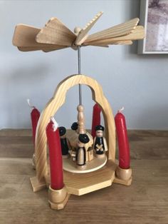 a wooden sculpture with candles and figurines in it sitting on a wood table