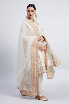 Daisy ivory flared kurta with Kashmiri tilla embroidered motifs and side panels. Comes together with salwar and silk organza dupatta enhanced with chanderi silk banarasi fabric border and pearls. 
Component: 3
Embroidered
Neckline: Mandarin Collar
Sleeve Length: Three Quarter
Fabric: Kurta: Chanderi Silk; Salwar - Bamber Satin; Dupatta: Silk Organza
Color: White
Concealed placket
Princess cut - Aza Fashions Tilla Embroidery, Salwar Pants, White Kurta, Organza Dupatta, Embroidered Neckline, Indian Fashion Designers, Silk Organza, Kurta Set, Designer Wear