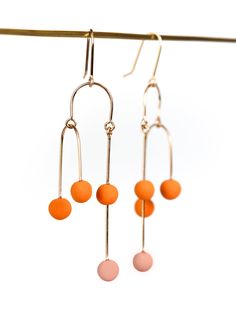 Clay Earrings - Perfectly balanced and exuding kinetic energy, these modern earrings are truly art in movement. An asymmetric, gold-filled wire creates a mesmerizing illusion, while the colorful, porcelain dancing dots add a playful touch. Gold-filled ear wires. Modern Wire Wrapped Drop Earrings, Modern Linear Drop Earrings For Jewelry Making, Modern Orange Earrings For Everyday Wear, Modern Wire Wrapped Earrings, Kinetic Earrings, Porcelain Earrings, Kinetic Energy, Asymmetrical Earrings, Artful Home