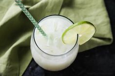 a close up of a drink in a glass with a green and white striped straw