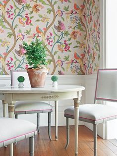 a white table with two chairs and a potted plant