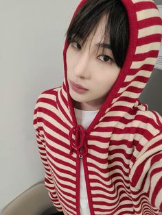 a woman wearing a red and white striped hoodie over her head, looking at the camera