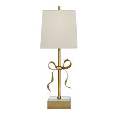 a gold lamp with a white shade on the base and a bow at the top