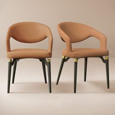 two brown chairs with black legs and one has a gold accent on the armrests