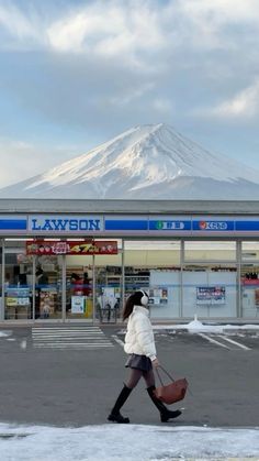 a woman walking across a parking lot holding two bags