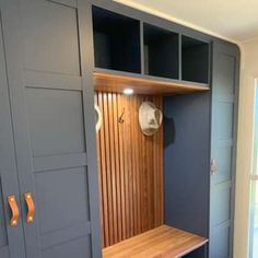 a wooden bench sitting inside of a room next to a wall mounted coat dryer