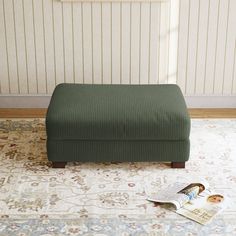 a green footstool sitting on top of a rug next to a magazine holder