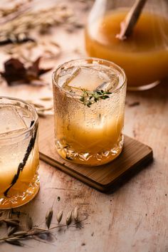 two glasses filled with drinks sitting on top of a wooden table