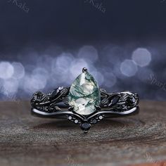 a ring with a green and white stone in it on top of a wooden table