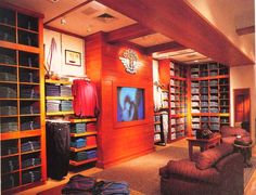 a room filled with lots of bookshelves next to a couch and chair in front of a flat screen tv