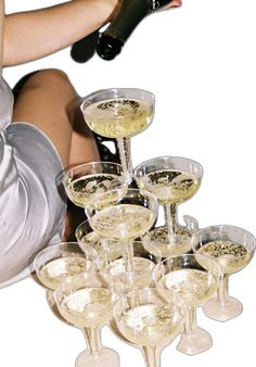 a woman is pouring champagne into wine glasses