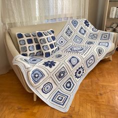 a blue and white crocheted afghan sits on a couch in front of a window