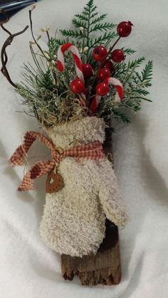 a vase filled with red and white flowers on top of a piece of wood covered in snow