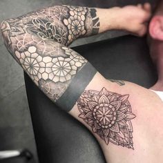 a man's arm with tattoos on it and an intricate flower design in the middle