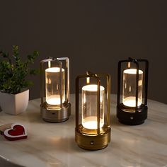 three lit candles sitting on top of a white table next to a potted plant