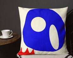 a blue and white pillow sitting on top of a chair next to a coffee cup