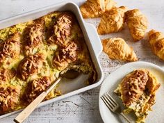 a casserole dish with meat and cheese on it next to croissants