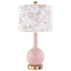 a pink table lamp with a gold base and white floral print fabric shade on it