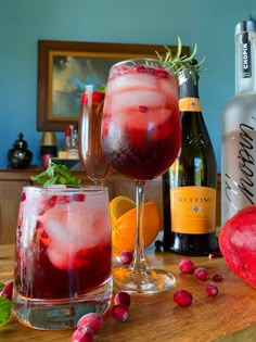 two wine glasses filled with liquid and garnish next to bottles of booze